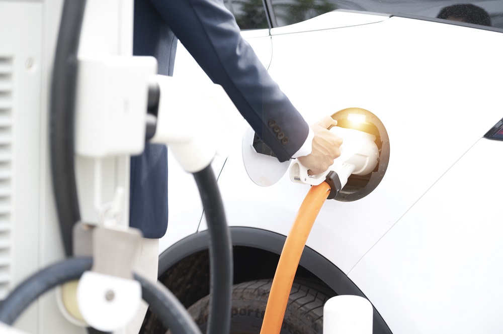 Mężczyzna w garniturze podpina samochód elektryczny do ładowarki